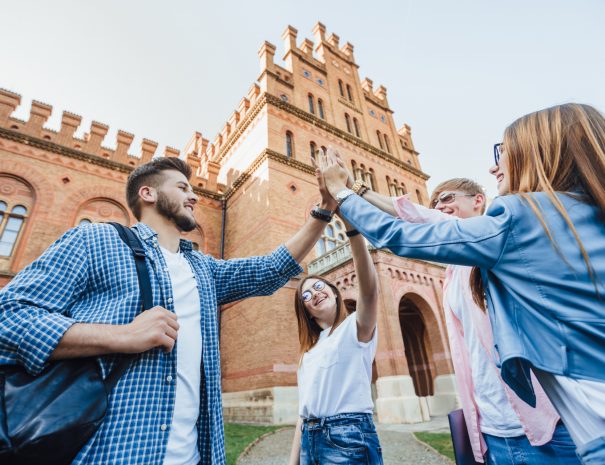 Low angle of cheerful team of students passed the test by preparing all together. Success, fun, friendship, education concept. Four graduates are celebrating outside. Casual clothes.